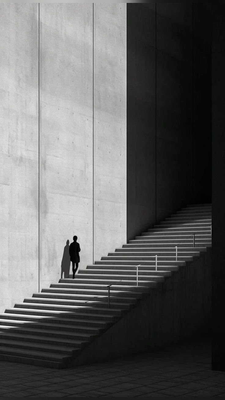 Image of a person walking up a staircase, surrounded by shadows